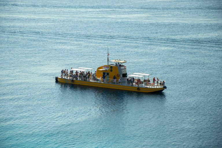 A bright yellow tourist boat carrying people on the ocean in a sunny day trip.